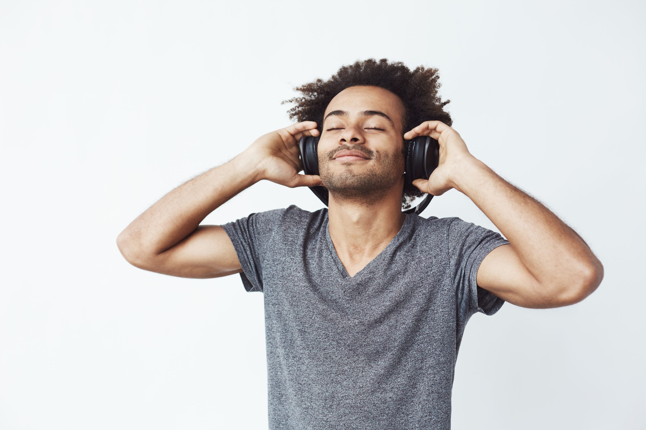 Happy african man smiling listening to music in headphones. Closed eyes