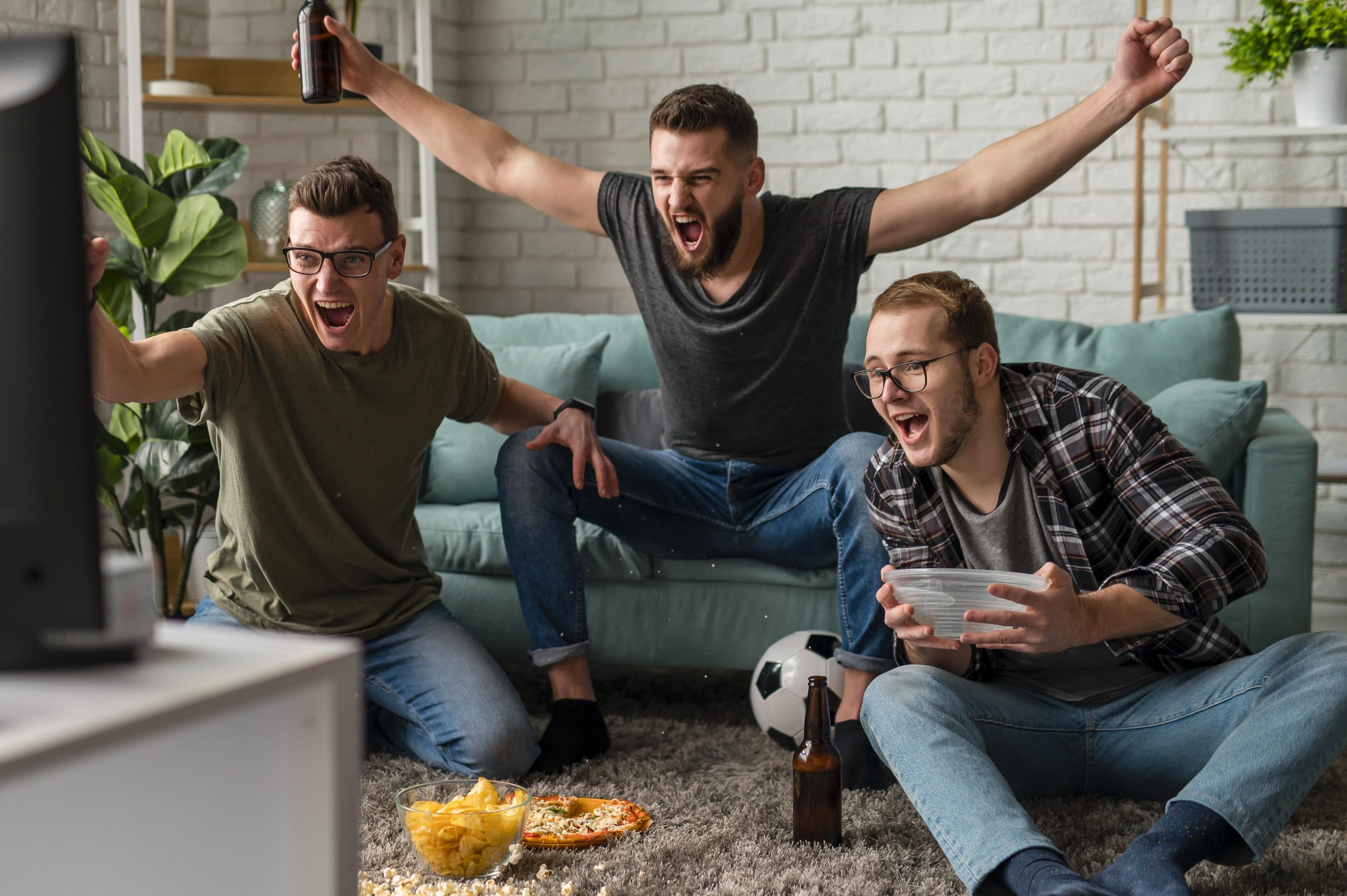 3 amigos em frente à TV assistindo futebol